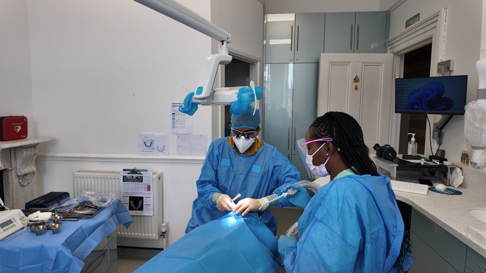 Principal dentist performing implant surgery under LED lamp