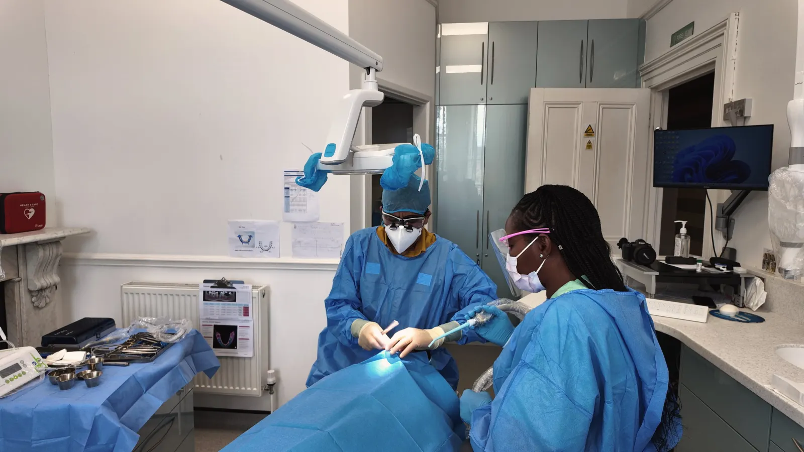 Principal dentist performing implant surgery under LED lamp