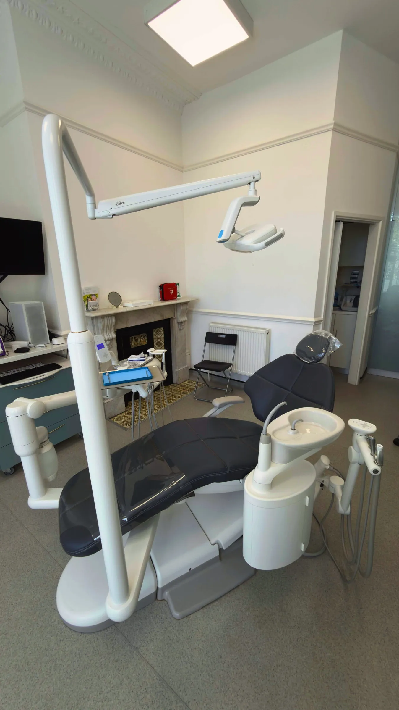 Second treatment room with charcoal dental chair and original marble fireplace